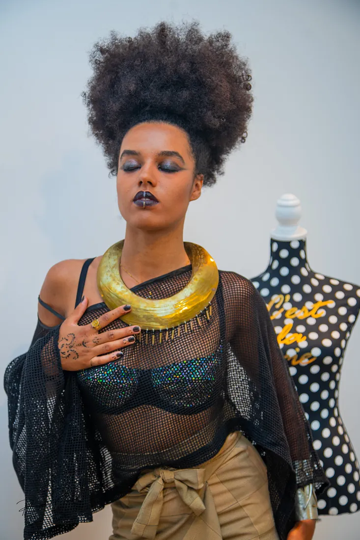 A brass collar and sheer black mesh beside a polka-dot mannequin