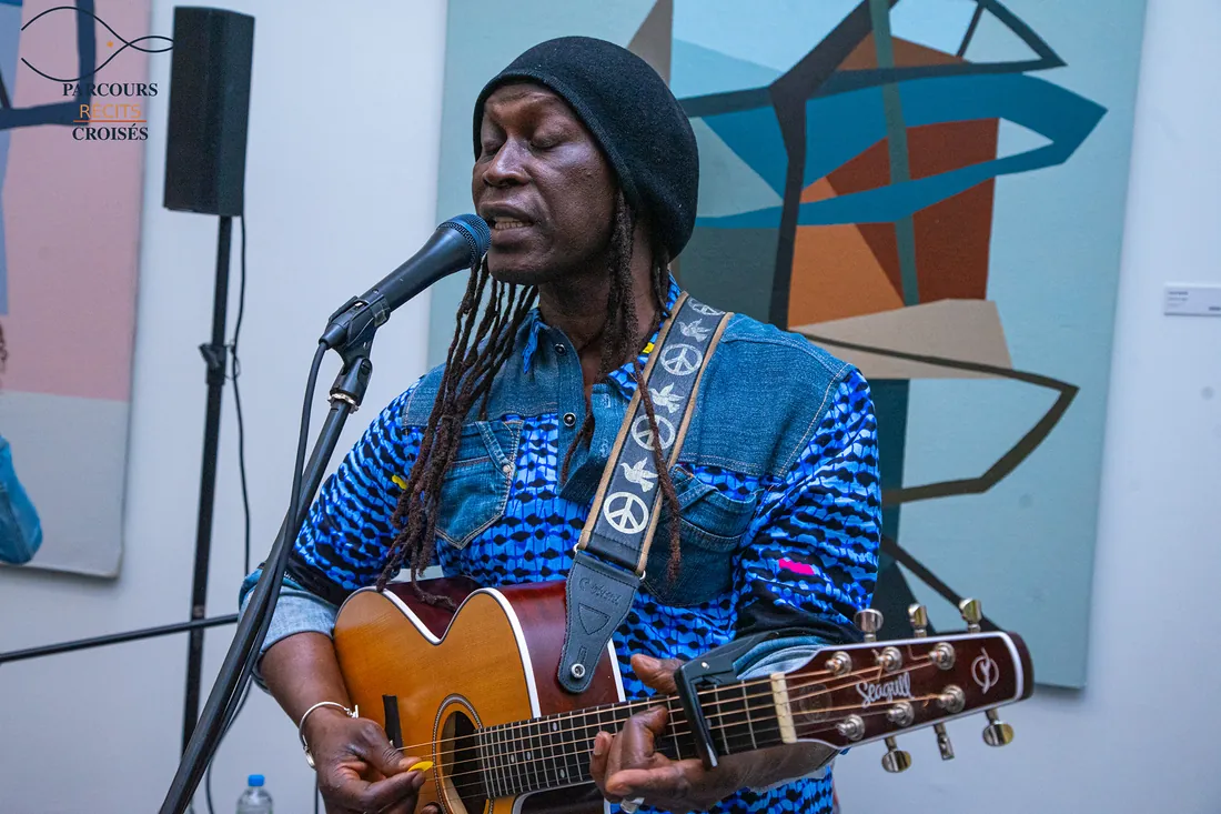 A guitarist sings between the paintings