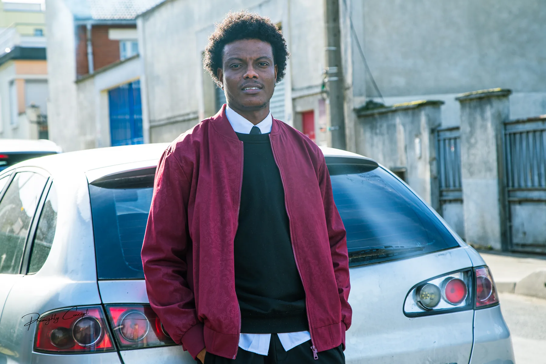 A burgundy bomber against a silver car